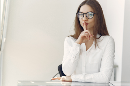 内緒のポーズをしている女性のイメージ画像。クレジットカードが無料で使える仕組みの“裏側”に迫る導入を象徴