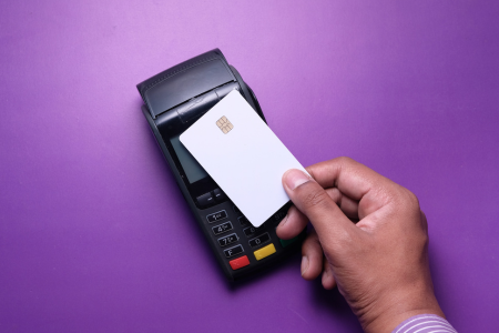 店頭でクレジットカードを端末にかざして決済している様子を捉えた画像。スマートで現代的な支払い方法を象徴する。